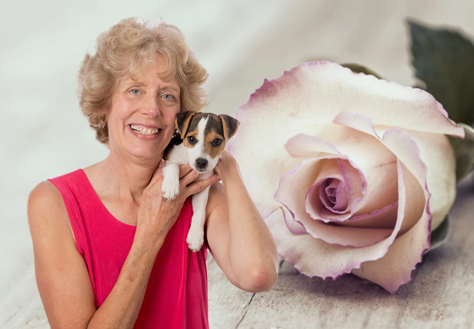 Dr. Cooke holding a small dog above her shoulder, with a pink rose in the background